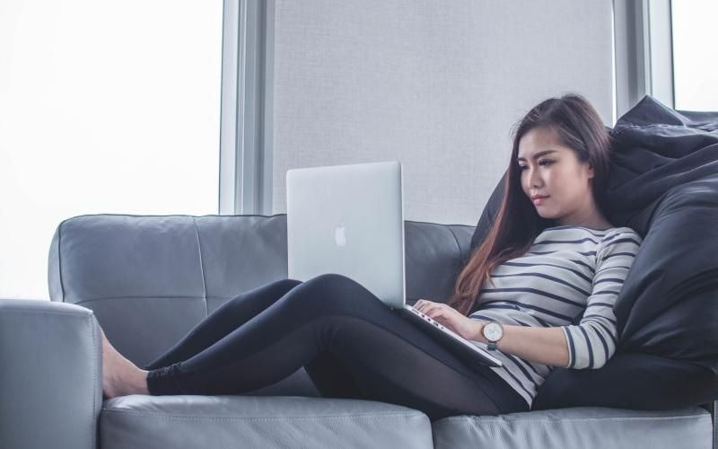 a person sitting on a couch with a laptop