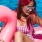a woman in a garment sitting on a pink float in the water